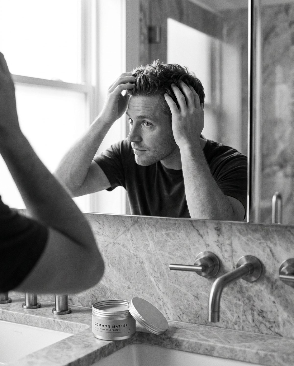 A man working No. 01 pomade through his hair at the mirror